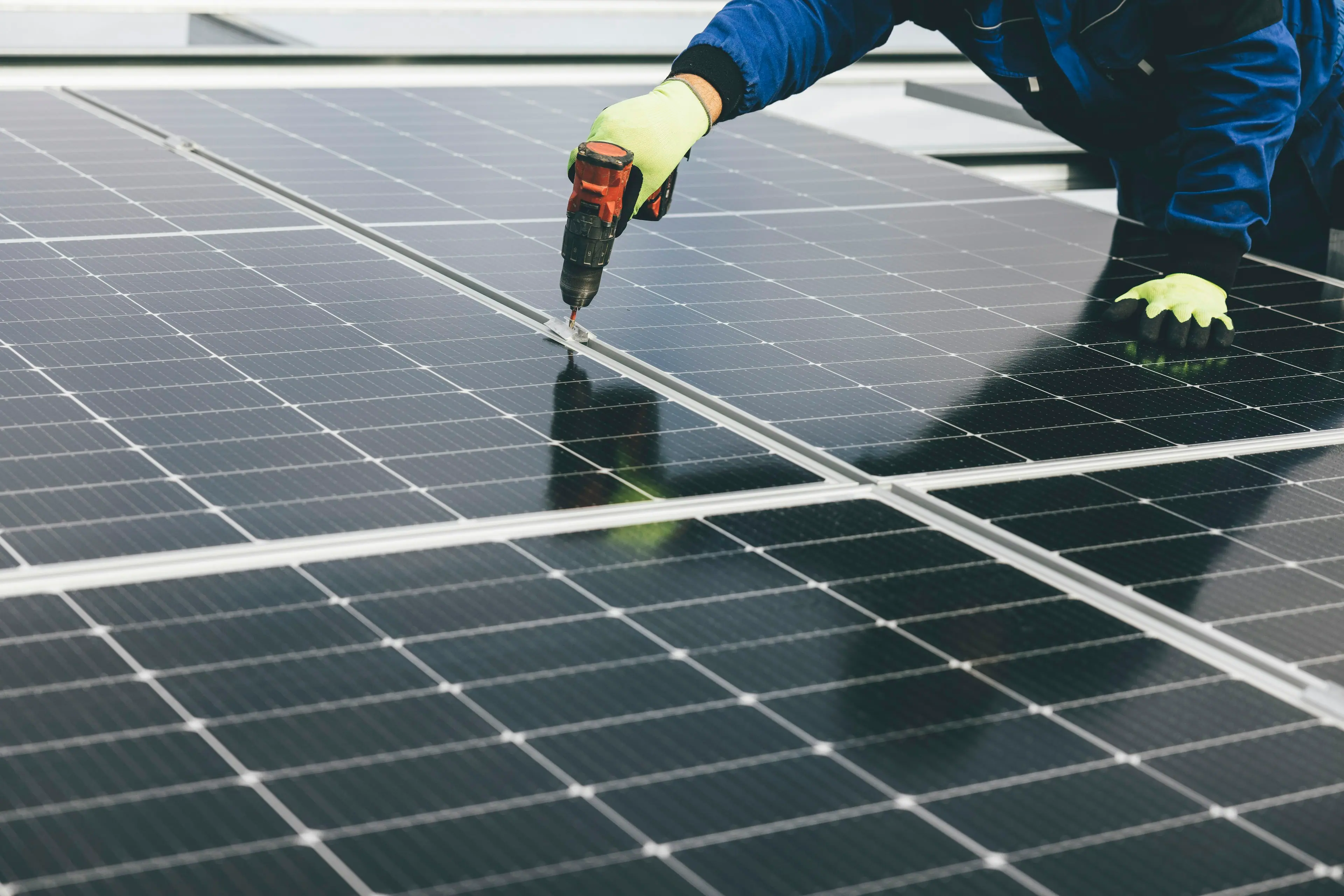 Solar installer fixing a panel to its mounting rail with a power drill
