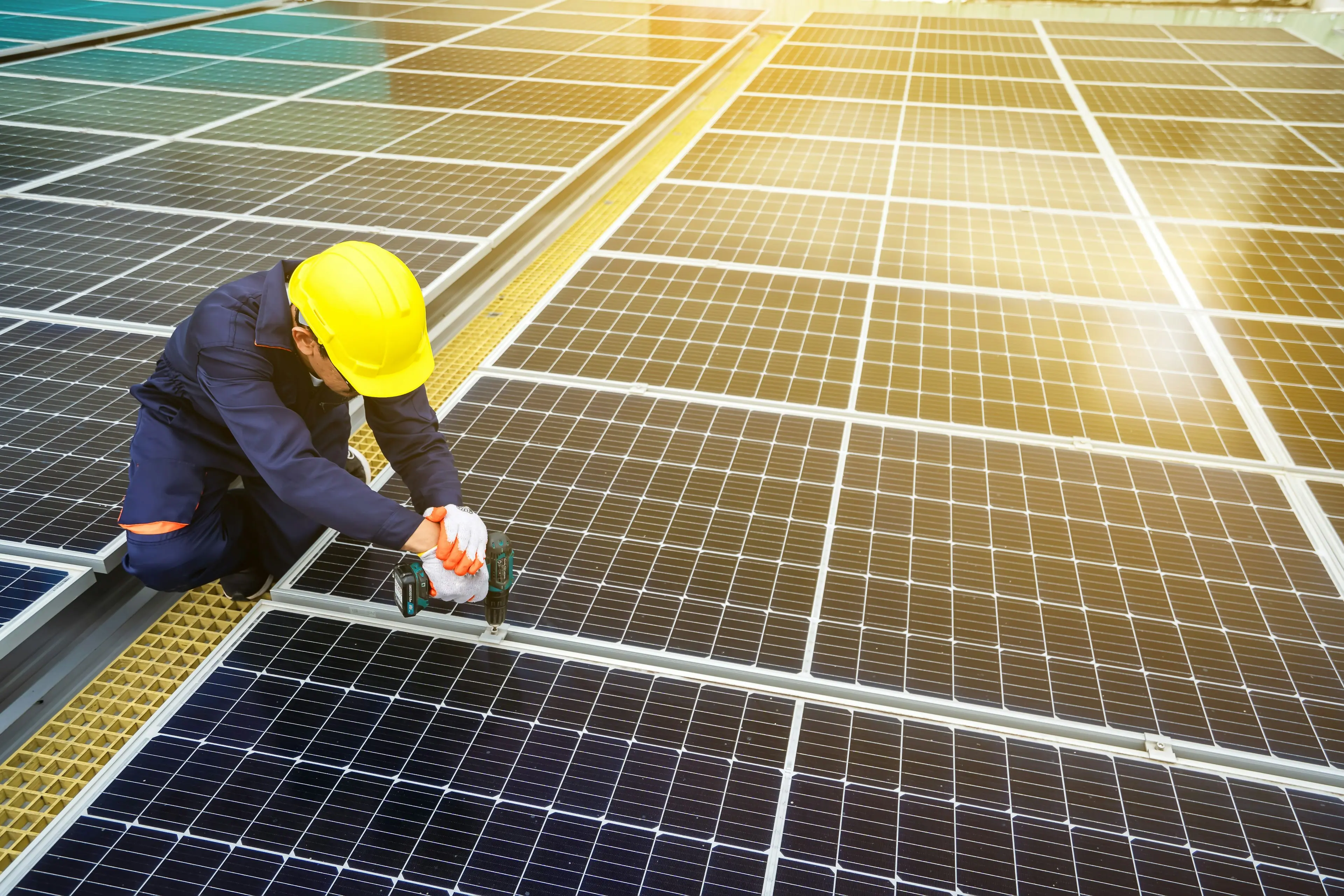 Solar technician in a hard hat installing rooftop solar panels